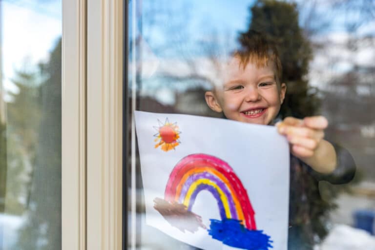 Young Boy sticking his drawing on home window.